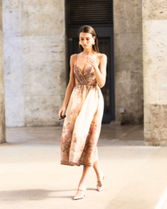 Woman in a soft paisley summer dress walking through an elegant stone walkway