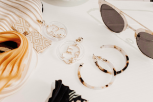 Elegant summer accessories with sunglasses, statement earrings, and soft neutral fabrics