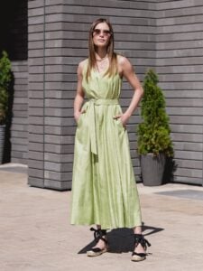 Woman wearing a light green belted summer dress with black sandals