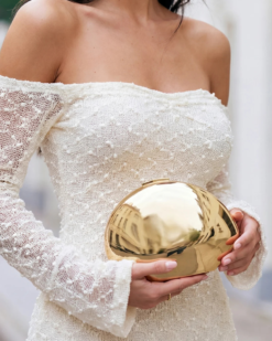 Gia Shell Evening Clutch in Gold in girl hands in white dress